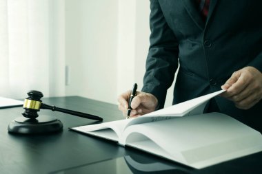 Avukat ya da yargıç elinde bir kalemle elinde bir terazi ve hukuk firmasında tokmağı olan bir masaya yasal belgeler yazacak.