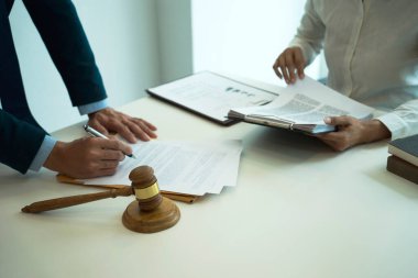 Hukuki dava ekipleri bir yargıcın tokmak masasında iş belgelerine danışmanlık ve taslak hazırlıyorlar..