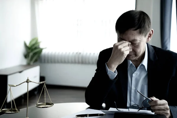 lawyer touch his nose  expressing a headache or discomfort while working on a client's lawsuit.
