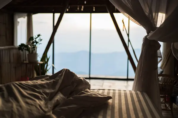 The cozy bedroom with the sunlight in the morning, nature green mountain in the bed.