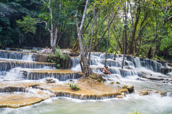 Tourist enjoying the view of beautiful waterfall in Thailand.