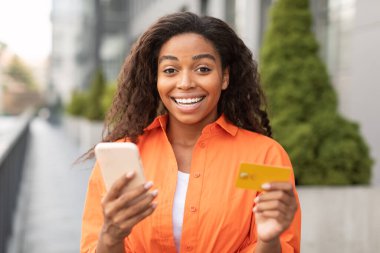 Bin yıllık Afro-Amerikan kadınlarının kredi kartı taşımasına ve şehir caddesinde para ödemek için akıllı telefon kullanmasına memnun oldum. Çevrimiçi alışveriş için yeni uygulama, nakit para iadesi ve kazanç, harika haberler ve reklam