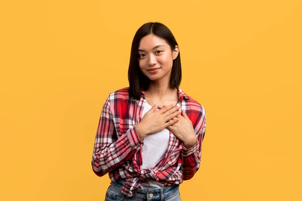 感谢的概念 感激的年轻中国女士手挽手 面带微笑 表达感激和善意 站在黄色的工作室背景之上 — 图库照片