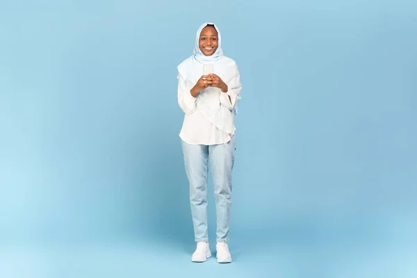 Afrykański Amerykański Muzułmanin Kobieta Pomocą Smartfona Stojąc Niebieskim Tle Studio — Zdjęcie stockowe