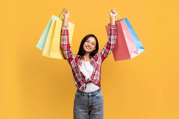 季节性销售的概念 欣喜若狂的亚洲女士拿着很多购物袋 女顾客对新买的东西感到高兴 摆出一副满屋子黄色的样子 — 图库照片