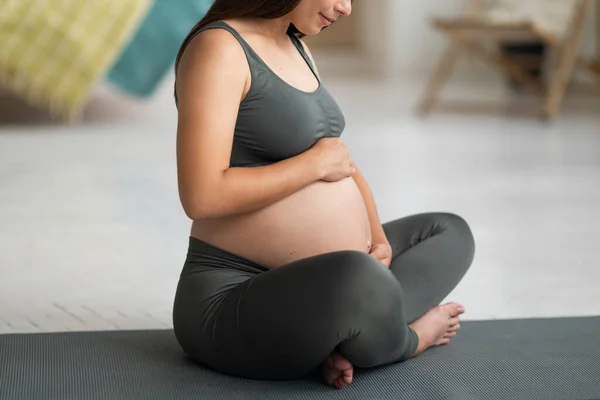 健康的な妊娠 自宅でヨガマットに座っている間に彼女の妊娠中の腹を受け入れる若い美しい女性の作物のショット アクティブで認識できない期待の女性高齢者の触手のおもちゃ — ストック写真
