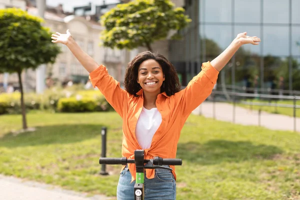 快乐的千禧年非洲裔美国女士 手拉手骑电动车 享受闲暇时间 享受良好的服务 在城市街道上散步 在公园外乘坐个人生态交通工具 乐趣无穷 — 图库照片