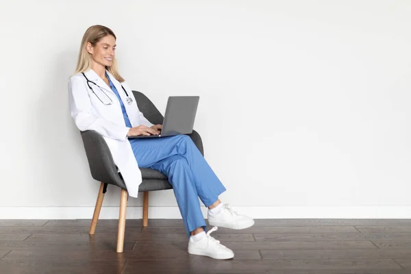 Moderne Medizin Lächelnde Ärztin Uniform Sitzt Stuhl Und Nutzt Laptop — Stockfoto