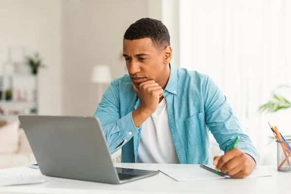 Serious Concentrated Young Black Man Jeans Looking Laptop Making Notes — Stock Photo, Image