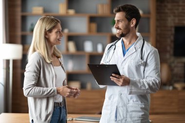 Tıbbi danışmanlık. Ofisteki toplantı sırasında üniformalı bir erkek doktor kadın hastayla konuşuyor. Stetoskop tutan profesyonel bir terapist ve klinikte gülümseyen kadına danışmanlık yapıyor.