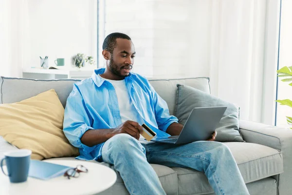 Bonito Homem Negro Com Laptop Cartão Crédito Sentado Sofá Compras — Fotografia de Stock