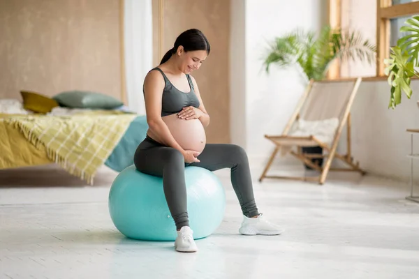 stock image Sport During Pregnancy. Beautiful Pregnant Female Sitting On Fitball And Embracing Belly, Smiling Young Expectant Woman In Activewear Training At Home, Enjoying Healthy Lifestyle, Copy Space