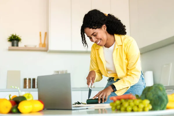 Cheerful Black Lady Cutting Organic Vegetables Using Laptop Cooking Food — Stock Photo, Image