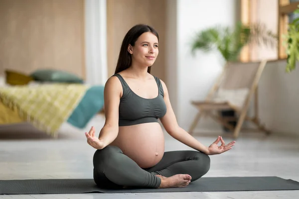 stock image Morning Meditation. Young Pregnant Woman Practicing Yoga In Lotus Position At Home, Millennial Expectant Female In Activewear Meditating On Fitness Mat In Living Room, Enjoying Healthy Lifestyle