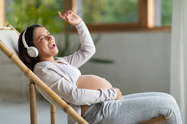 Joven Mujer Embarazada Alegre Escuchando Música Mientras Relaja Silla Casa —  Fotos de Stock