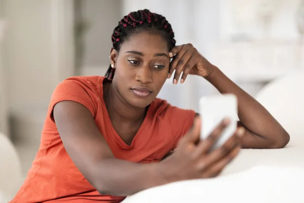 Страстная Афроамериканская Женщина Смотрит Экран Смартфона Сидя Дома Диване Расстроенная — стоковое фото