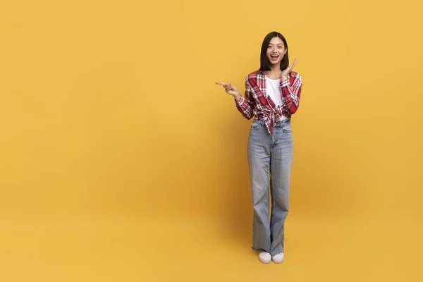 特別オファーだ 黄色のスタジオの背景 全身の長さ バナーの上に孤立立ってコピースペースで指を脇に指して興奮した韓国人女性 広告のための場所を示す正の女性 — ストック写真