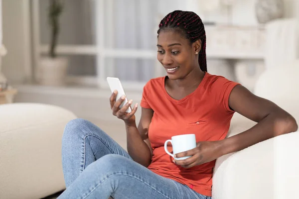Häusliche Freizeit Lächelnde Schwarze Frau Die Mit Smartphone Und Kaffee — Stockfoto