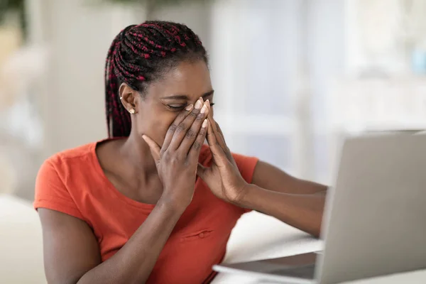 目の疲労 自宅でラップトップを使用した後に疲れている若い黒人女性 コンピュータとマッサージ鼻橋で机に座って千年アフリカ系アメリカ人フリーランスの女性 閉鎖ショット — ストック写真
