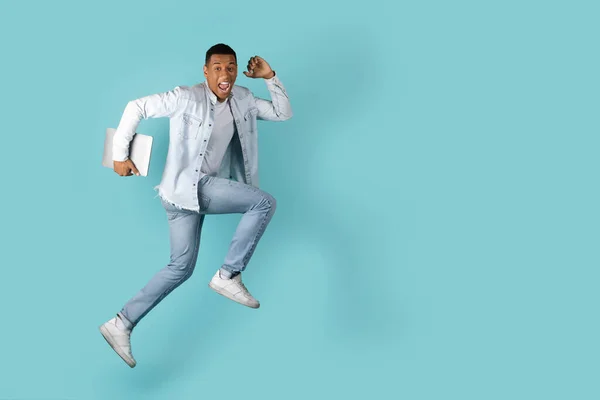 밀레니엄 아프리카 미국인을 웃으면서 벌리고 공간으로 노트북을 점프하는 스튜디오에 고립된 — 스톡 사진