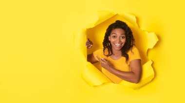 Afro-Amerikalı Kadın Parmak Yanı Poz Veriyor Yırtık Kağıt Deliği 'nde. Sarı Stüdyo Arkaplanında Yazı İçin Boş Yer Gösteren Kadın. Şuraya bak konsept. Panorama