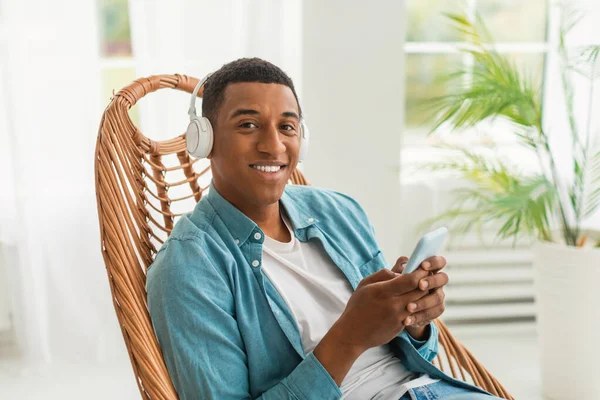 Ευτυχισμένη Χιλιετή Αφροαμερικανός Άνδρας Ασύρματα Ακουστικά Smartphone Στηρίζεται Καρέκλα Και — Φωτογραφία Αρχείου