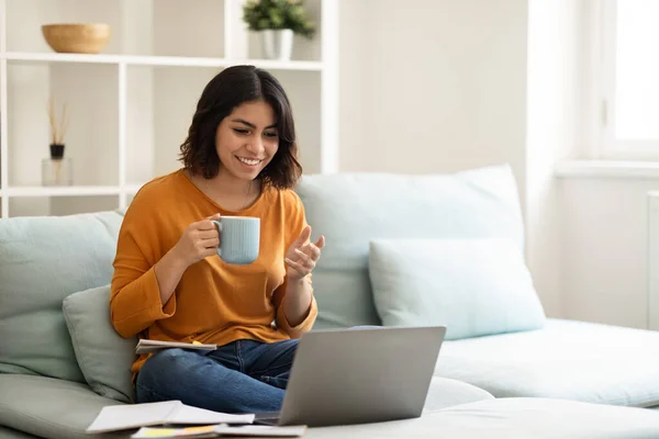 在线交流 快乐的阿拉伯女人在笔记本电脑上打视频电话 在家喝咖啡 快乐的中东女人与朋友聊天 享受热饮 复制空间 — 图库照片