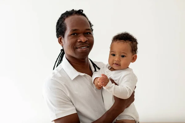 stock image Father And Baby. Portrait Of Smiling Young Black Dad Posing With Adorable Toddler Child In Hands While Relaxing Together At Home, African American Man Bonding With His Cute Little Son, Copy Space