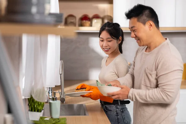 동양인 부부가 집안일을 아름다운 아내가 설거지를 사랑하는 접시를 말리고 대화와 — 스톡 사진