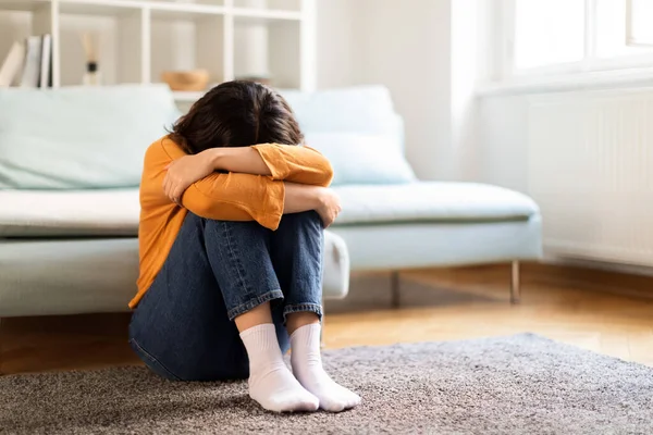 抑郁症的概念 忧心忡忡的年轻中东女人在家里哭泣 沮丧的千禧年女人坐在房间地板上头埋在膝盖里 精神崩溃 复制空间的刻画 — 图库照片