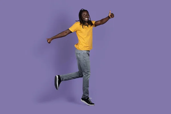 보라색 스튜디오 배경에서 평상복 차림으로 공중에서 점프하는 머리를 아프리카 미국인 — 스톡 사진