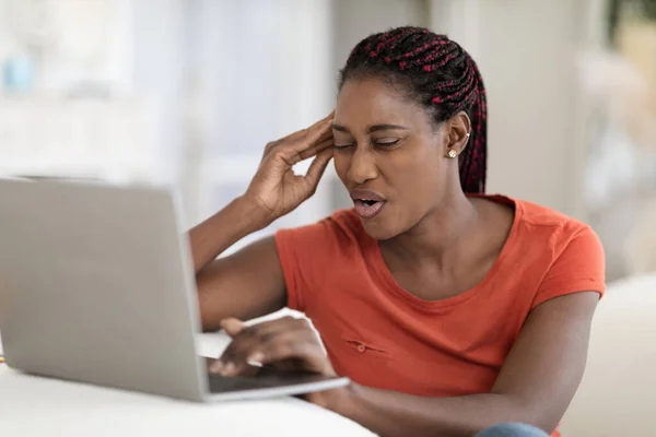 Portrait Of Stressed Young Black Freelancer Lady Having Headache While Using Laptop, African American Woman Sitting At Desk In Home Office And Touching Head, Suffering From Acute Migraine, Closeup