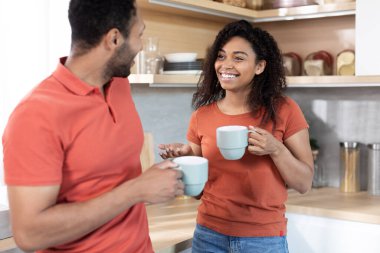 Mutlu, mutlu, genç, siyah koca ve bardakları en sevdiği sıcak içecekle dolu güzel bir eş sohbetin tadını çıkarın, sabah akşam mutfak içinde boş zaman ve hafta sonu. Kahve molası, aşk ve evde ilişkiler.