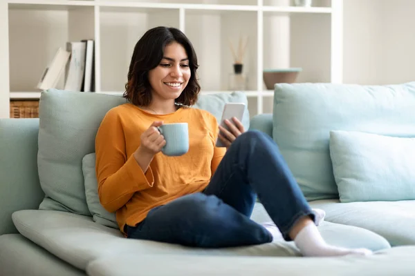 Lazer Fim Semana Sorrindo Mulher Árabe Relaxante Sofá Com Smartphone — Fotografia de Stock