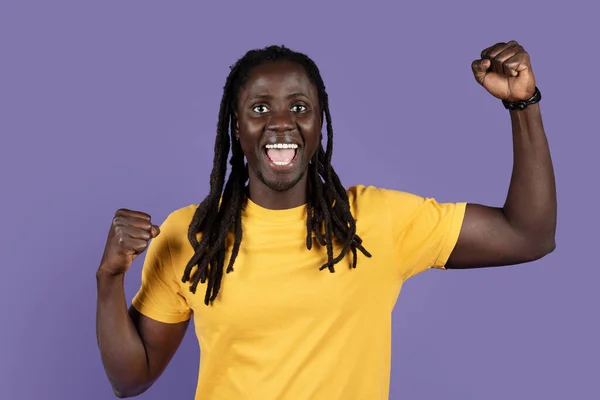 人間の感情の概念 感情的なハンサムな長髪ミレニアル黒男で黄色Tシャツ調達拳アップと叫んで上の紫のスタジオの背景 お祝いの成功 — ストック写真