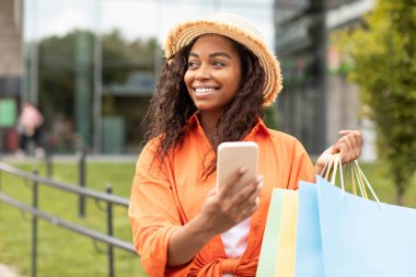 Şapkalı, akıllı telefondan daktilo eden, bir sürü paket taşıyan, şehirde yürüyüş yapan, fotokopi alanına bakan bin yıllık siyahi bir kadın olmasına sevindim. Modern mobil cihaz ve çevrimiçi alışveriş uygulaması, büyük indirim