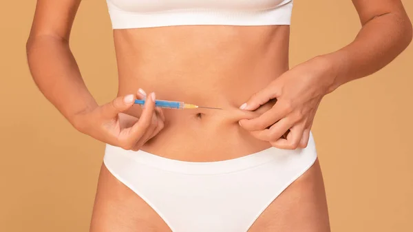 体の輪郭 認識できない女性は腹への脂肪分解注射を作ります 注射器を使用して女性のクローズアップショット 皮膚に針を挿入 ベージュスタジオの背景 — ストック写真