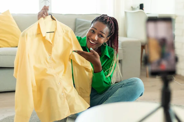 stock image Happy black female blogger making video review with new clothes after successful online shopping, recording video on cellphone at home. E-commerce and fashion blogging career concept