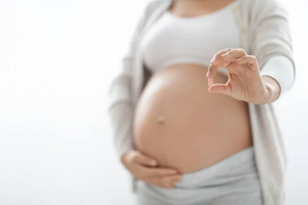白い背景の上に薬の丸薬を保持している認識できない妊娠中の女性 ビタミンやサプリメントを取って大きな腹を持つ女性を期待 クロップ 妊娠中の健康管理 — ストック写真