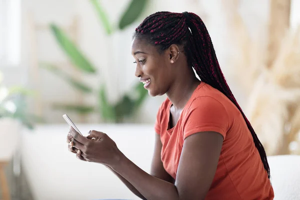 Mensagens Móveis Sorrindo Mulher Negra Usando Smartphone Enquanto Descansa Sofá — Fotografia de Stock