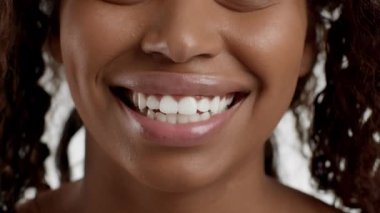 Profesyonel diş hijyeni. Kameraya gülümseyen, beyaz dişlerini gösteren, ağır çekimde genç ve güzel Afrikalı Amerikalı bir kadının portresini yakından çek.