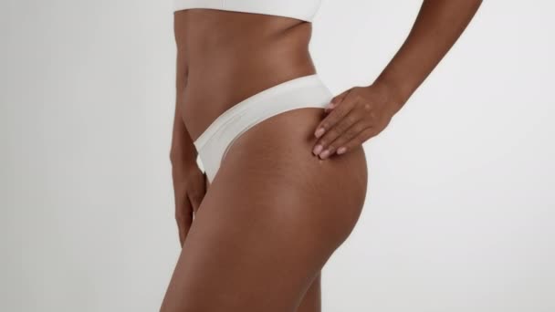 抗セルライトボディケア 閉じる上のショットの認識できないアフリカ系アメリカ人女性でアンダーウェア摩擦皮膚リフティングクリーム上の腰の皮膚 白いスタジオの背景 スローモーション — ストック動画