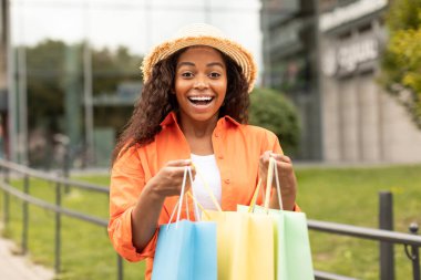 Neşeli, duygusal, bin yıllık şapkalı siyahi kadın bir sürü paket açıyor, satın almaktan hoşlanıyor, şehirde gezmekten hoşlanıyor. Alışveriş, büyük indirim, büyük sipariş, moda blogu ve şehir yaşam tarzı