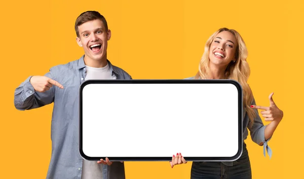 Aufgeregtes Junges Paar Zeigt Auf Großes Smartphone Mit Weißem Bildschirm — Stockfoto