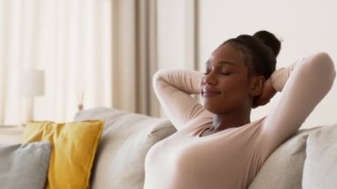 Rahatlama zamanı. Kapalı kapılar ardında, evinde dinlenen genç, barışçıl Afrikalı Amerikalı bir kadının portresi. Kanepede gözleri kapalı oturuyor. Ellerine yaslanıyor.