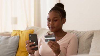 Çevrimiçi ödeme başarılı. Genç Afrikalı Amerikalı kadın internet üzerinden ödeme yapıyor, akıllı telefon ve kredi kartıyla bankacılık uygulaması kullanıyor, çekim takibi, yavaş çekim, serbest alan