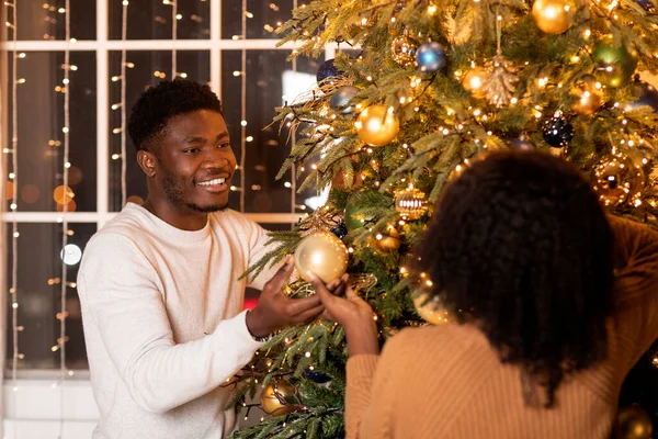 Neşeli Genç Siyah Çift Noel Ağacını Çelenklerle Oyuncaklarla Dekorla Süslüyor — Stok fotoğraf
