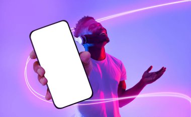 Duygusal Afrikalı genç Amerikalı adam, neon ışıkta müzik dinliyor, en yeni kablosuz müzik kulaklığını dinliyor, modern akıllı telefonu beyaz ekranlı gösteriyor, model, kolaj, kopyalama alanı