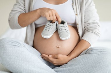 Evde pijamalı bir bayanın kucağında şirin bebek paçaları, tanınmayan bir annenin çocuk kıyafetleri ve ayakkabıları alması beklenir.