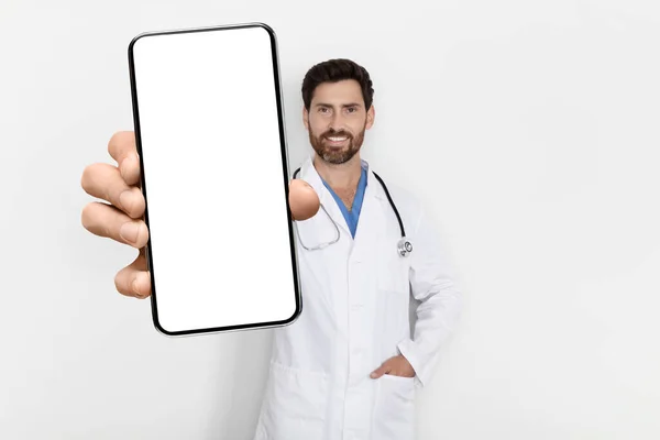 Tıbbi Uygulama Üniformalı Yakışıklı Doktor Kamerada Büyük Boş Akıllı Telefonu — Stok fotoğraf